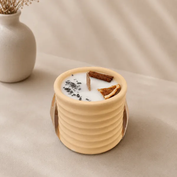 Vela artesanal Aura Abundancia en recipiente de ceramica beige con canela y naranja