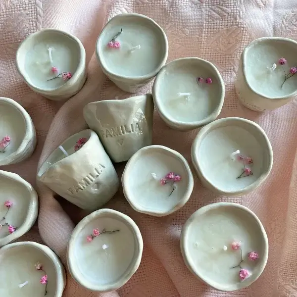Velas de cerámica artesanal con paniculata rosa sobre tela, detalle de boda